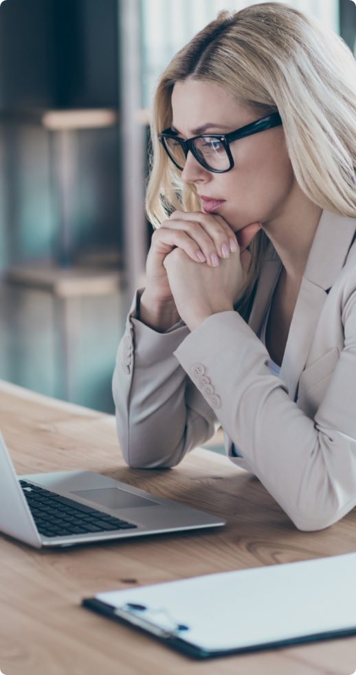 Młoda kobieta z długimi prostymi blond włosami, w okularach z czarnymi oprawkami, siedząca przed laptopem.